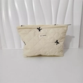 Detail of quilted cotton makeup bag featuring black bow patterns and zipper closure - Cosmetic Bag Creamy White