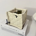 Detailed view of cream quilted storage bin with black bow embroidery and fabric texture - Off White