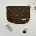Vista dettagliata di una borsa da trucco in velluto a coste marrone con motivi a fiocco - Borsa da trucco marrone con fiocco
