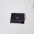 Close-up of black quilted pouch with butterfly embossing and white snap button closure - Mini Bowknot Necklace / Black