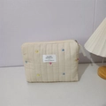 Close-up of quilted cream makeup bag with colorful heart embroidery and zipper detail - Off-white Heart Embroidered Clutch