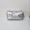 Detail of silver quilted makeup bag with embossed bow patterns and fabric label - Small Bow Silver