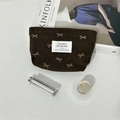 Trousse à maquillage en velours côtelé marron avec nœuds et accessoires sur fond clair - Petit sac à rouge à lèvres marron avec nœud