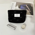 Dettaglio ravvicinato di una trousse nera in velluto a coste con motivi a fiocco e logo - Borsa per rossetto nera con fiocco