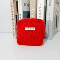 Detail view of red plush square pouch with mayrabbit label on minimalist book background - Bright Red