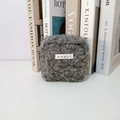 Detail of grey plush cosmetic bag with a small woven label on a clean background - Gray