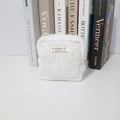Nahaufnahme der weißen Plüschtasche mit mayrabbit-Webetikett auf einem Tisch - Weiß