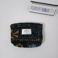 Detail of plush leopard print makeup bag with colorful geometric patterns and white label - Maple Leaf Plaid