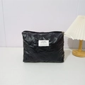 Detail showing black quilted PU makeup bag with bow embossed pattern and brand label - Small Bow Black