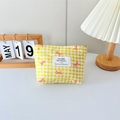 Detail of yellow checkered canvas makeup bag with floral bow print on white desk - Checkered Print Bow Yellow