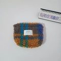 Close-up of thick plaid Sherpa plush storage pouch with decorative woven label - Colored Grid