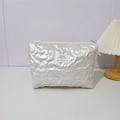 Détail d'une trousse à maquillage matelassée en PU avec zip doré et étiquette de marque - Grand Cœur Blanc Cassé