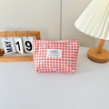 Close-up of red plaid canvas makeup bag with blue bows and soft lighting background - Checkered Print Bow Red
