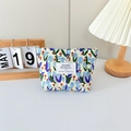Detail of floral canvas cosmetic bag with blue tulip print and brand label on front - Floral Tulip Blue