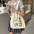 Détail du sac cabas en toile brodé avec motifs fleurs et oiseaux dans un café - Sac Bandoulière Cordon Broderie Éponge Mignon : Petite Fleur Hirondelle (Beige)