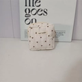 Détail du motif cœur matelassé et de l'étiquette May Rabbit sur la trousse à maquillage beige - Petit sac carré blanc crème