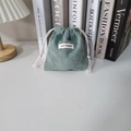 Detalle de la bolsa de cordón de pana verde grisáceo con etiqueta tejida May Rabbit - Verde Hierba