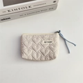Detail of quilted heart pattern fabric pouch with zipper puller and brand tag - Khaki