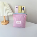 Pink nylon cosmetic pouch with blue zipper and brand label on a minimalist desk - Vertical Style / Pink