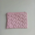 Detail of pink heart-quilted pouch featuring silver zipper closure and smooth texture - Pink