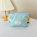Close-up of light blue macaron makeup bag with pink zipper and brand label details - Horizontal Style / Blue