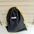 Detail of black Oxford fabric pouch with vibrant yellow drawstring and brand woven label - Black Large