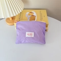 Detail of purple fabric mini cosmetic pouch featuring yellow zipper and pink ring pull - Horizontal Style / Purple