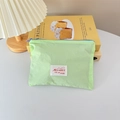 Close-up of mint green makeup pouch with Mayrabbit label on yellow books - Horizontal Style / Green