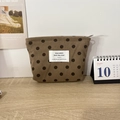 Detailed shot of dark brown polka dot corduroy storage bag with zipper on wooden table - Brown Polka Dot Lipstick Bag