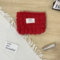 Close-up of red bubble textured canvas makeup bag with a minimalist brand label - Bubble Red