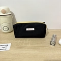 Detailed view of large capacity black nylon pencil case with yellow zipper and white label - 19x6x7cm / Black