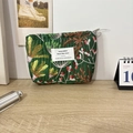 Detailansicht der dunkelgrünen gesteppten Tasche mit Blumenmuster auf einem Holztisch - Fluoreszierende Kosmos Grün