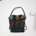 Detail of plush crossbody bag with geometric patterns, woven strap and gold bead closure - Maple Leaf Plaid