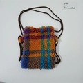 Close-up of colorful checkered plush mini crossbody bag with a brown woven rope strap - Colored Grid