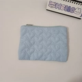 Close-up of heart-quilted light blue cosmetic bag with silver zipper and fabric texture - Blue