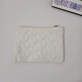 Detail view of the white quilted heart pattern and smooth zipper on this mini pouch - White