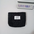 Detail of heart quilted black lipstick pouch with a white woven label and minimalist style - Black