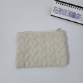 Close-up of heart-shaped quilted pattern and zipper detail on beige mini makeup bag - Khaki