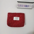 Macro view of red heart-shaped quilted makeup bag with white woven brand label - Burgundy