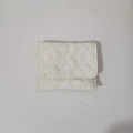 Macro detail of white heart-quilted fabric texture and circular button on mini pouch - White