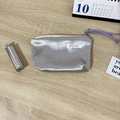 Close-up of silver metallic makeup bag with purple drawstring on a wooden desk - Satin Silver