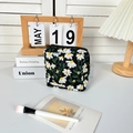 Detail einer Kosmetiktasche aus Stoff mit Gänseblümchen-Stickerei und Goldreißverschluss - Damenbinden-Tasche / Schwarz