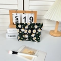 Detail der weißen Gänseblümchenstickerei auf schwarzer Stoff-Kosmetiktasche mit Reißverschluss - Kleine Clutch / Schwarz