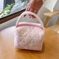 Detailed view of pink quilted makeup bag with heart pattern and sturdy top handle - Pink
