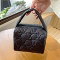 Close-up of black quilted makeup bag with zipper closure and portable top handle - Black