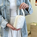 Close-up of a white quilted mini vanity bag with a soft padded texture and top handle - White