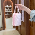 Detail of pink quilted cosmetic bag with heart pattern texture and zipper closure - Pink