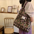 Lifestyle shot of floral tulip canvas tote bag with May Rabbit label in a cozy cafe - Black