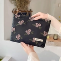 Close-up of floral rose embroidery and brand label on black fabric cosmetic storage bag - Black Lotus Pink Rose