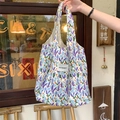 Close-up of floral canvas tote bag with purple tulips and brand label in vintage setting - Blue